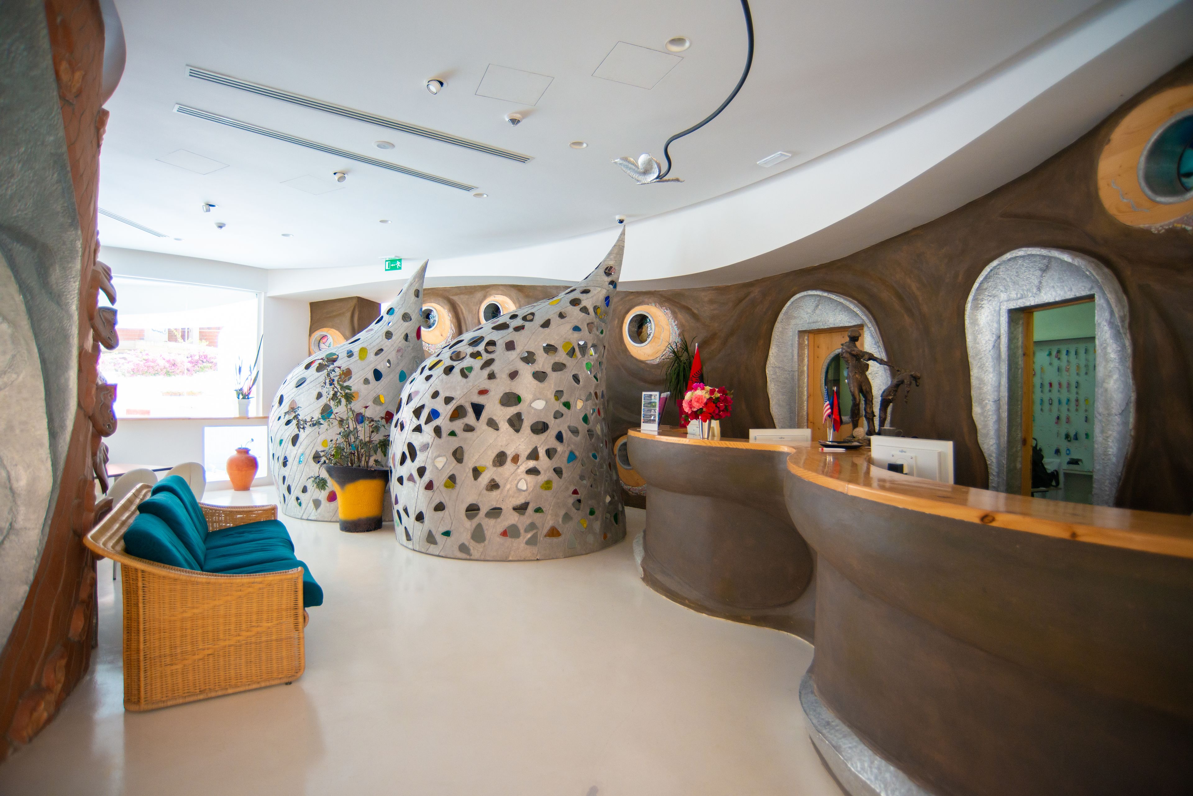 A lobby with a reception desk, wicker furniture, and decorative walls.