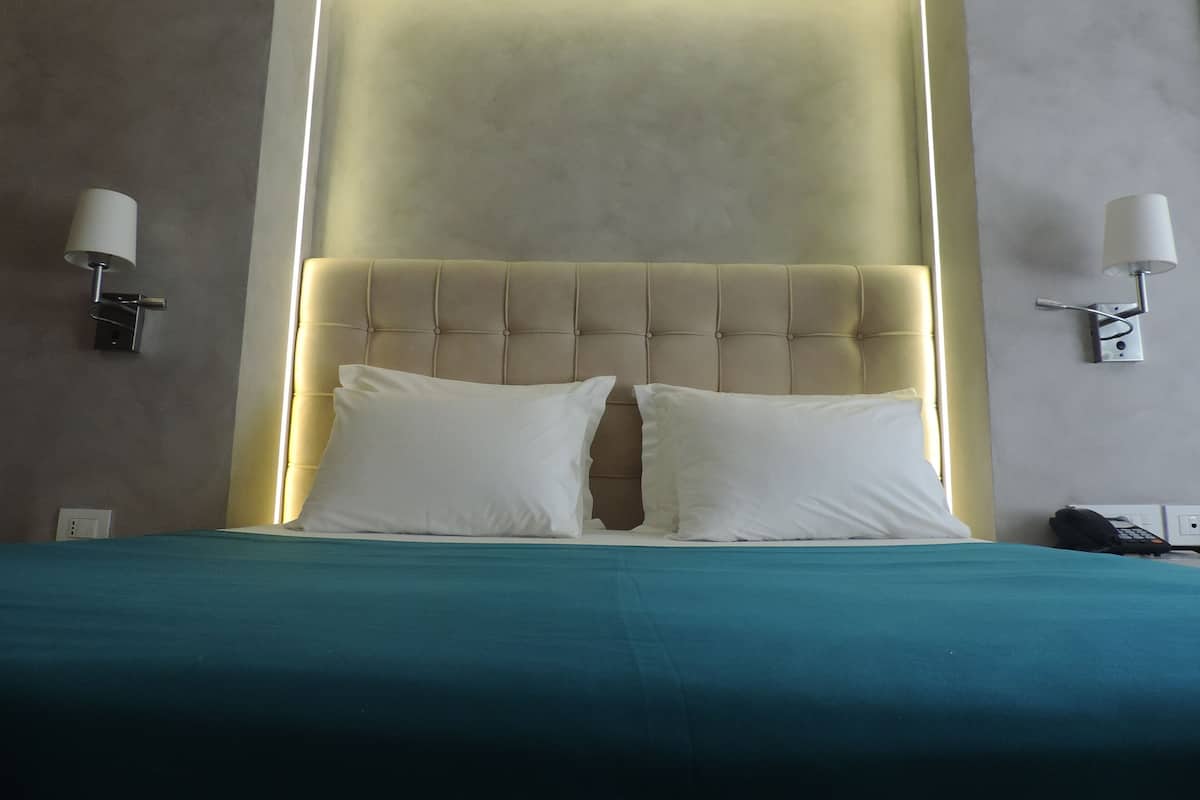 Een hotelkamer met een groot bed, twee bedlampen en een modern hoofdeinde.