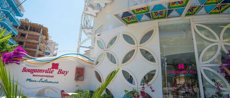 Un edificio con fachada blanca, múltiples ventanas y un letrero que dice "Bougainville Bay Beach Art & Resort".