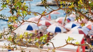 Une vue sur la plage, avec des parasols et une rambarde.