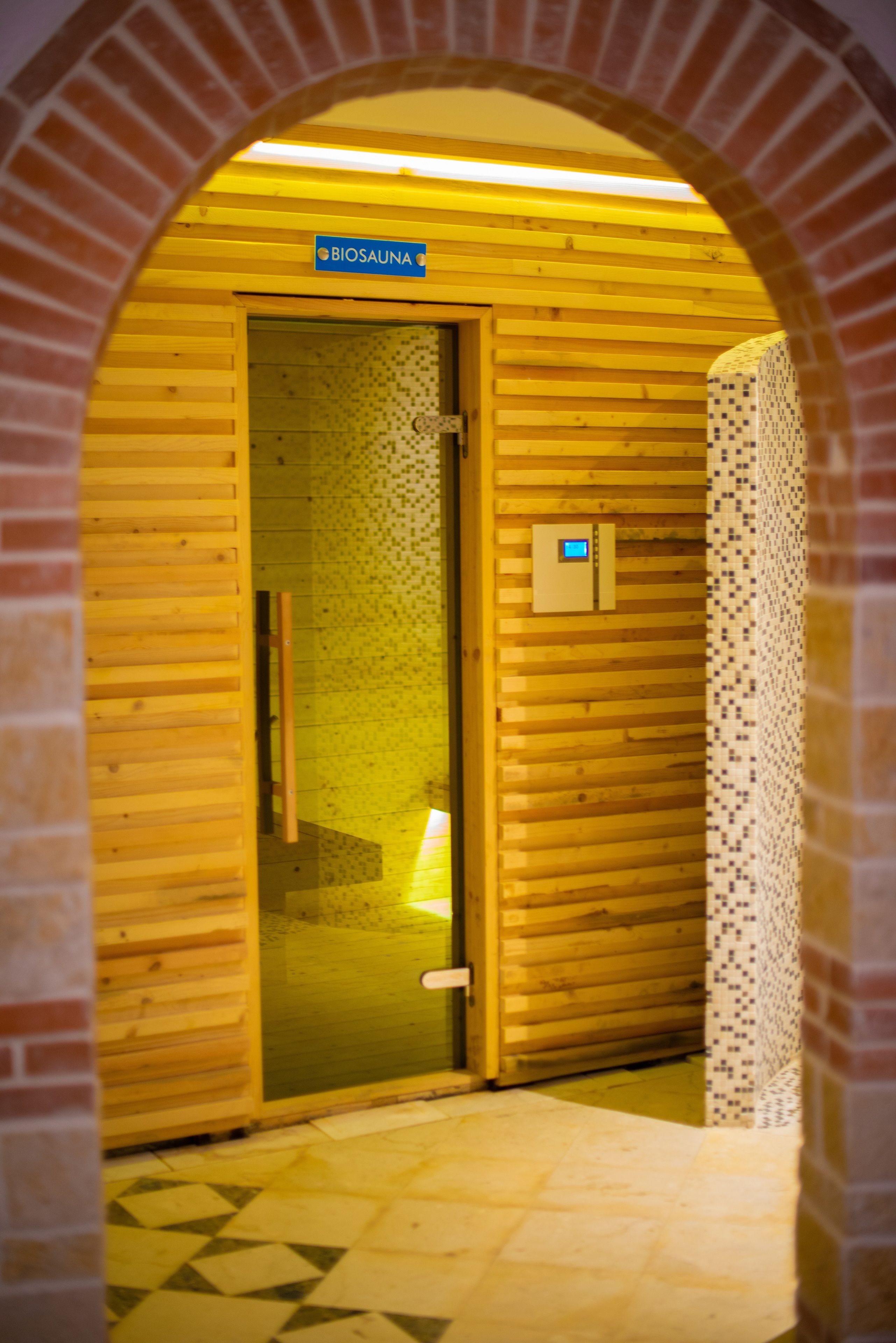 Une entrée en forme d’arche, en bois, menant à une pièce portant l’inscription « BiosauNA ».