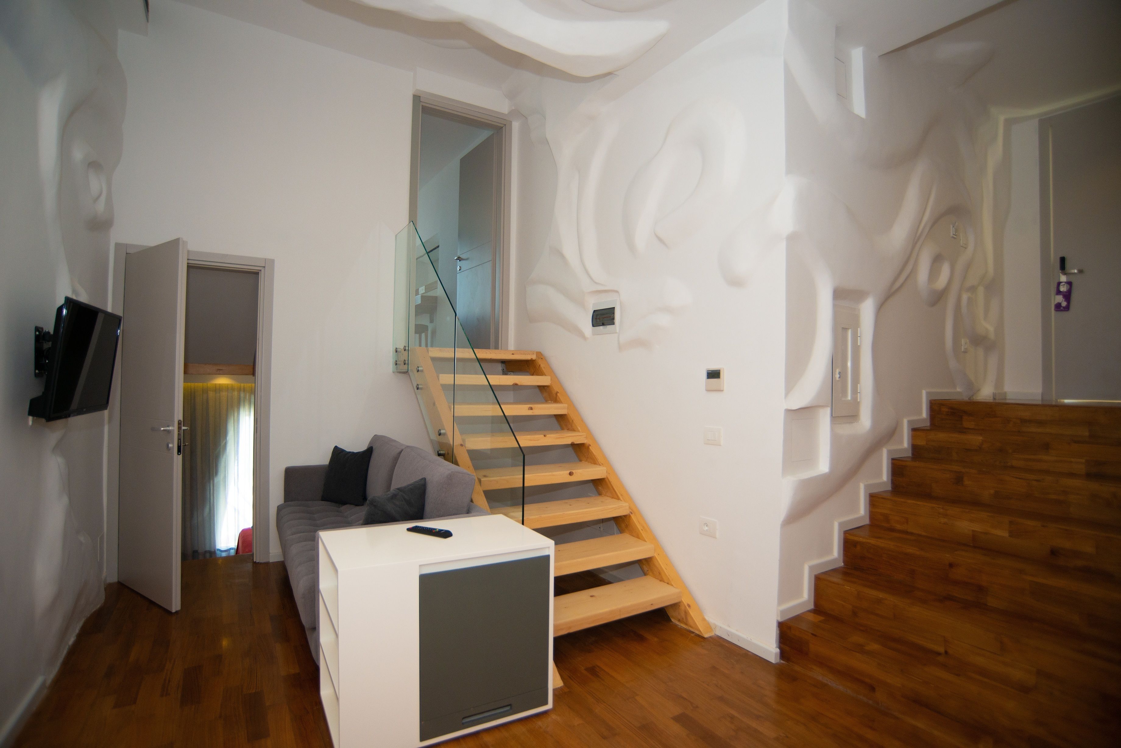Un intérieur moderne avec un escalier en bois, un canapé et un téléviseur.