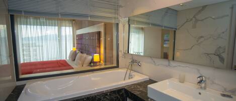 A modern bathroom with a large bathtub, a separate sink, and a large mirror.