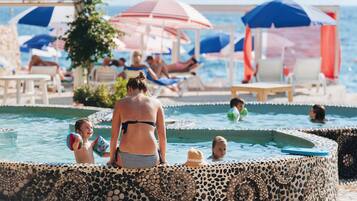 Relax by the pool surrounded by a beautiful mosaic border, with comfortable lounge chairs and shaded areas.