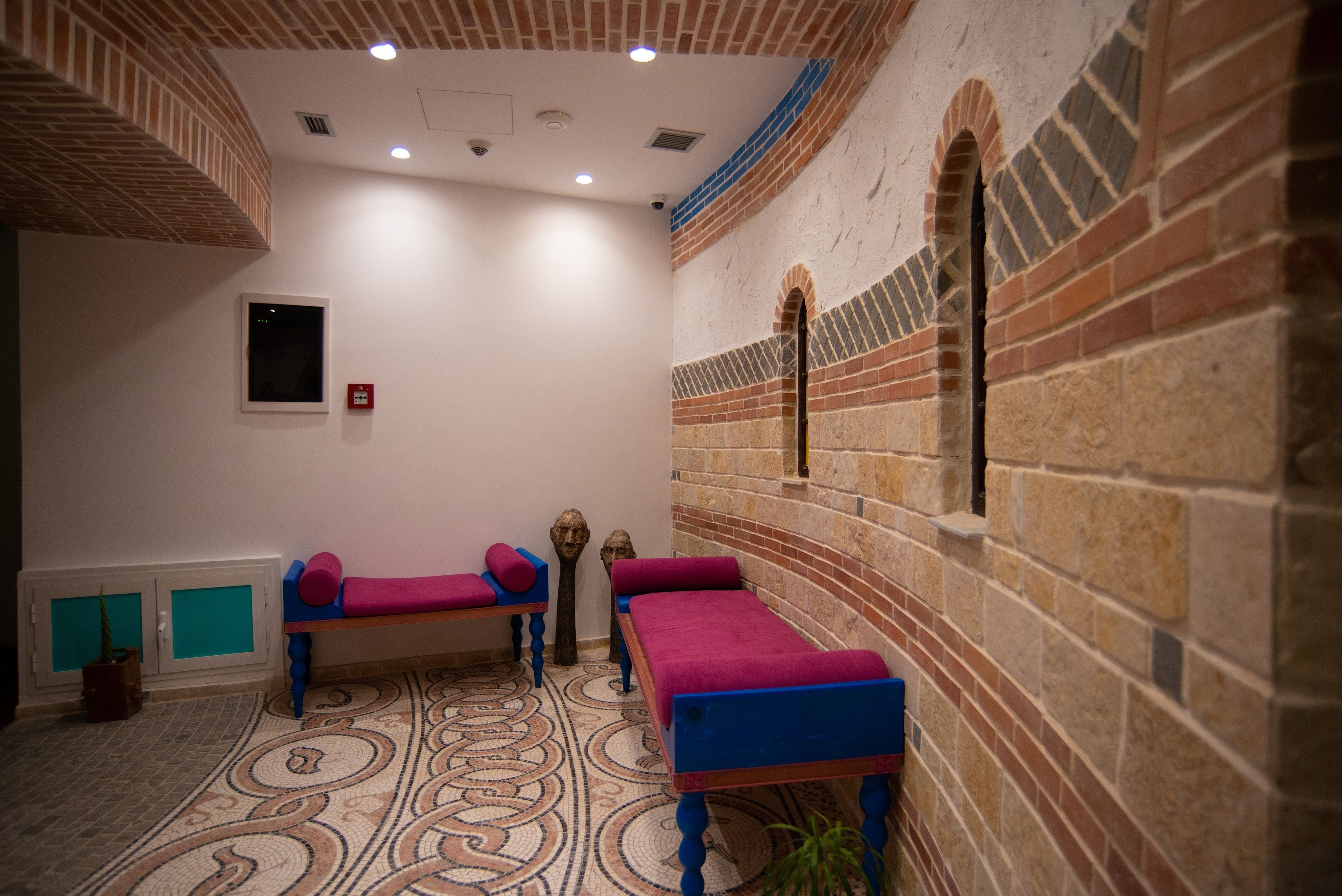 A room with two wooden beds, a patterned floor, and brick walls.