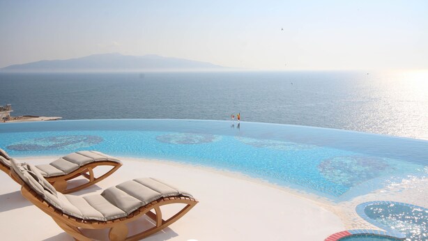Un espace aménagé au bord de la piscine, avec des chaises longues et une vue sur la mer.