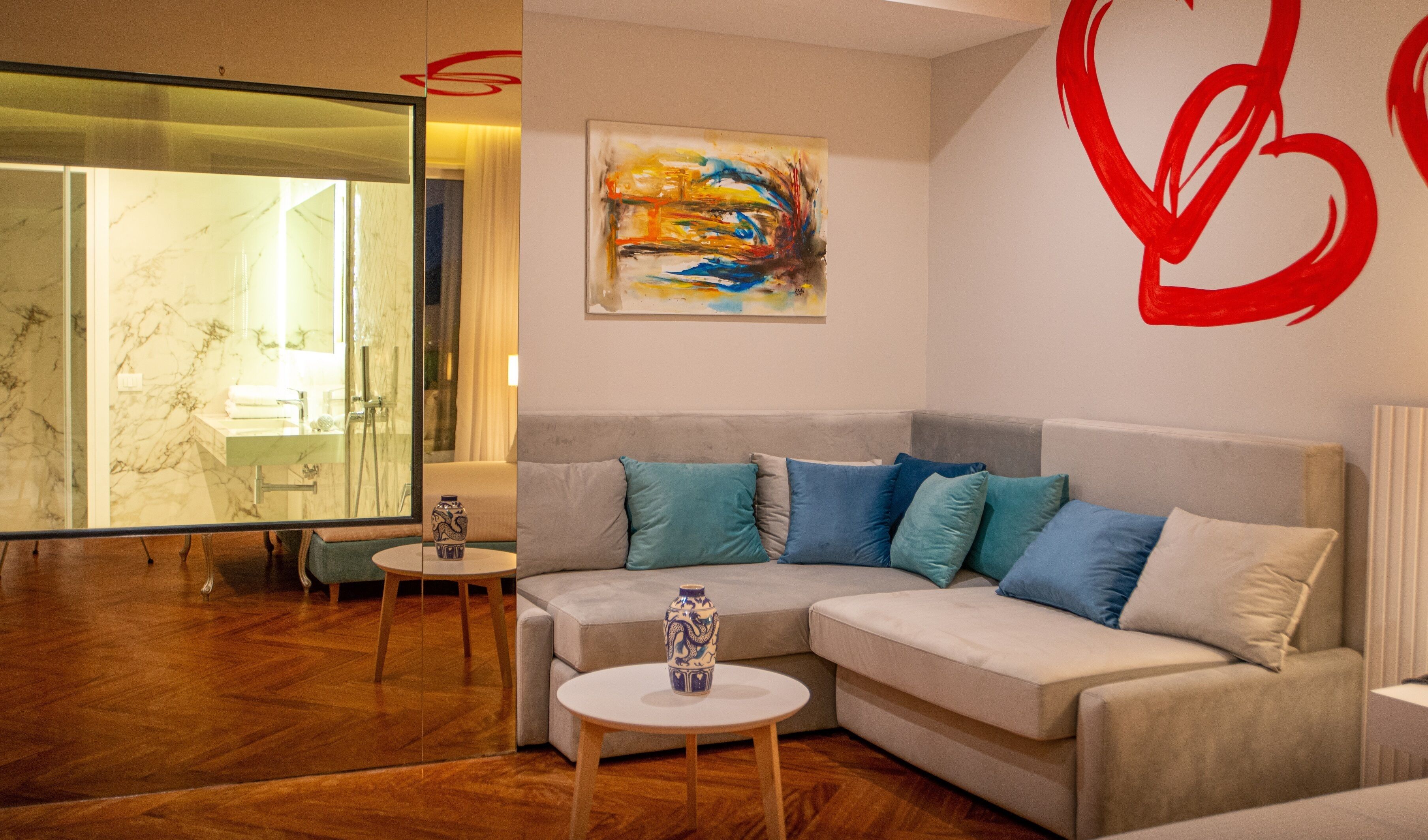 A modern living room with a beige sofa, blue and white cushions, a round coffee table, and a glass shower area.