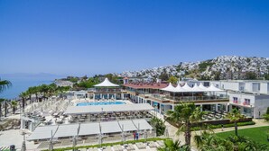 A resort with a pool, outdoor seating, and a view of the sea and hillside town. - Armonia Holiday Village & Spa (Bodrum)
