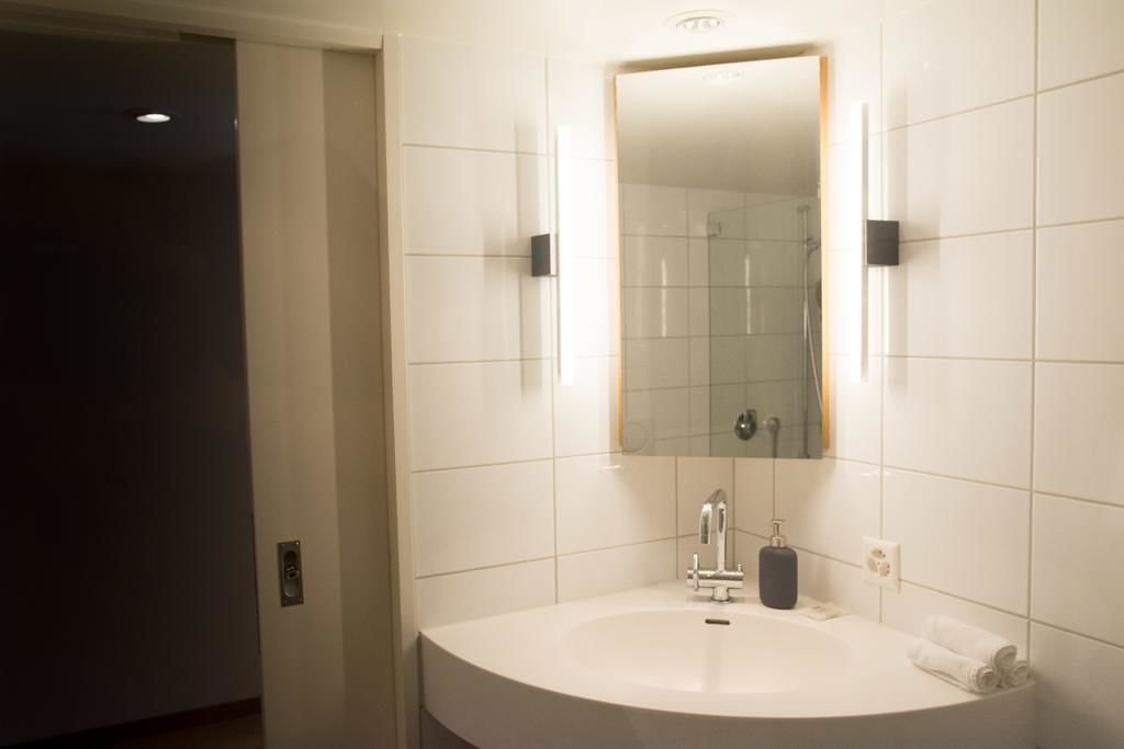 A bathroom with a white sink, a mirror, and a glass shower enclosure.