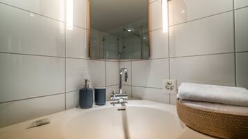 Ein modernes Badezimmer mit einem großen Waschbecken, einem Spiegel und einem Handtuchhalter.