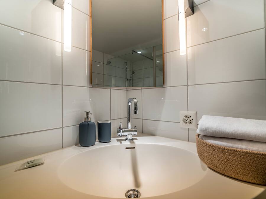 Ein modernes Badezimmer mit einem großen Waschbecken, einem Spiegel und einem Handtuchhalter.