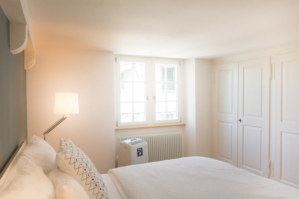 A bedroom with a bed, a radiator, a window with shutters, and a wardrobe.
