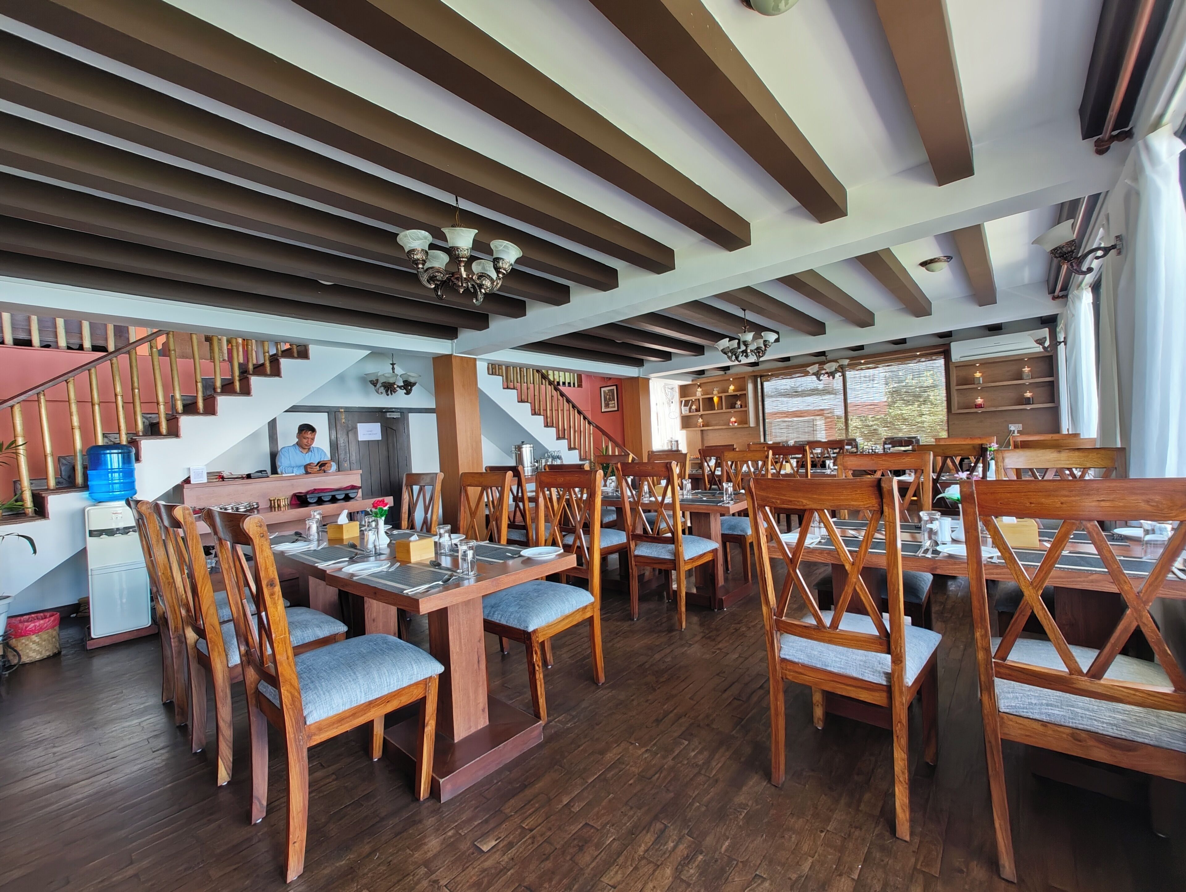 Een restaurant met houten meubels, een trap en een waterdispenser.