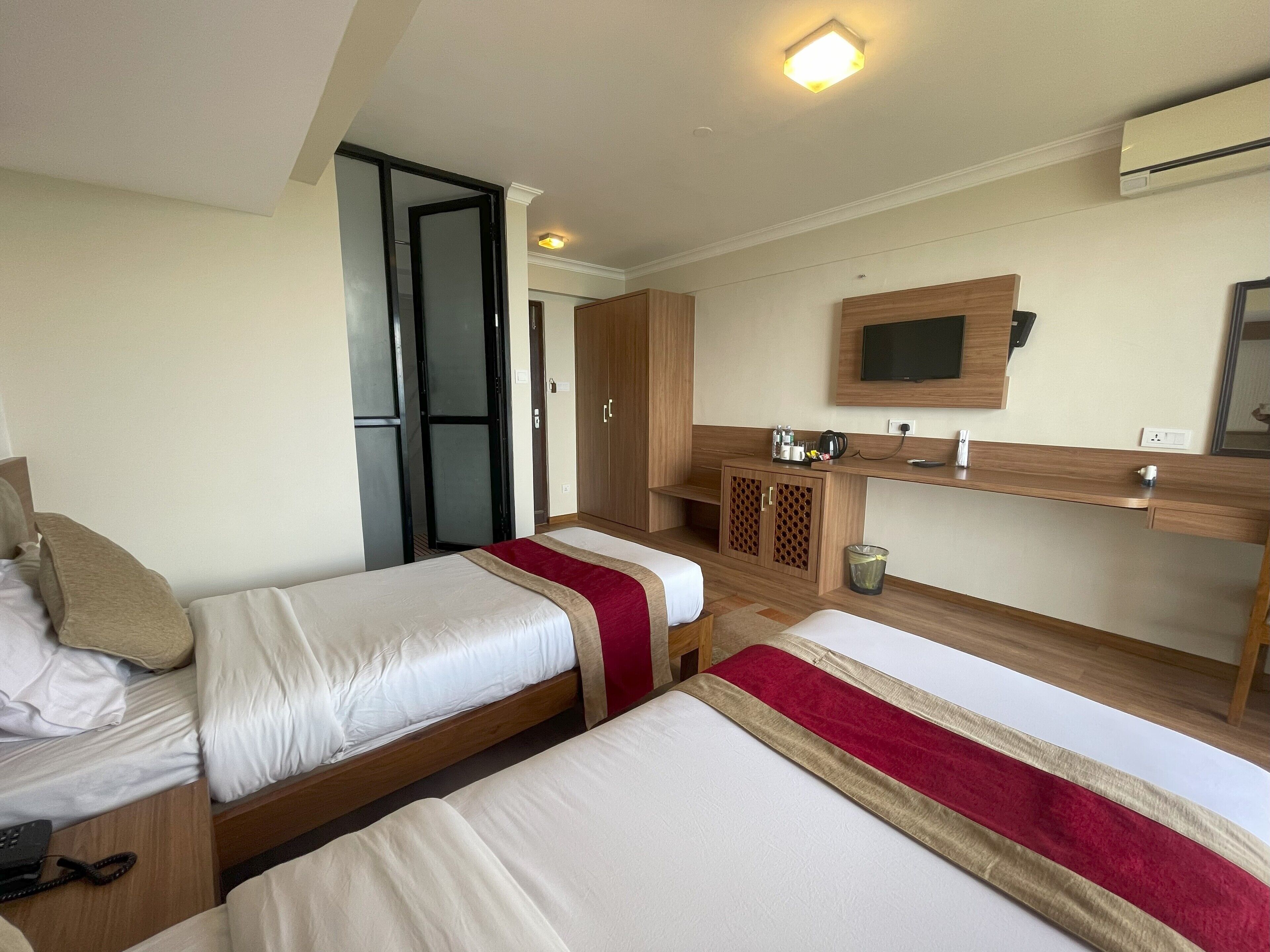 A hotel room with two beds, a TV, a minibar, and a wardrobe.