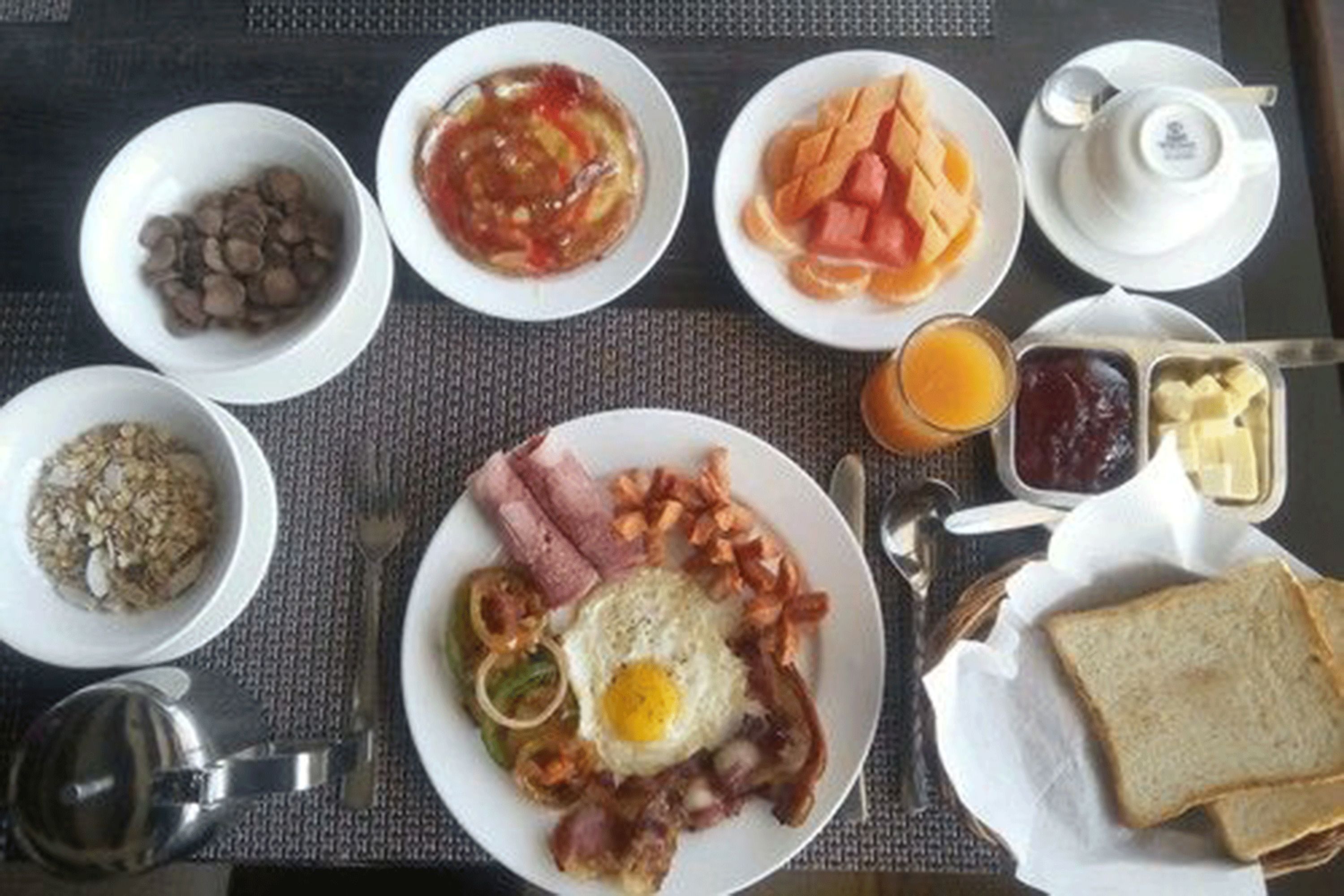 Un assortiment de plats pour le petit-déjeuner comprenant divers éléments, notamment des œufs, du bacon, des toasts et des fruits.