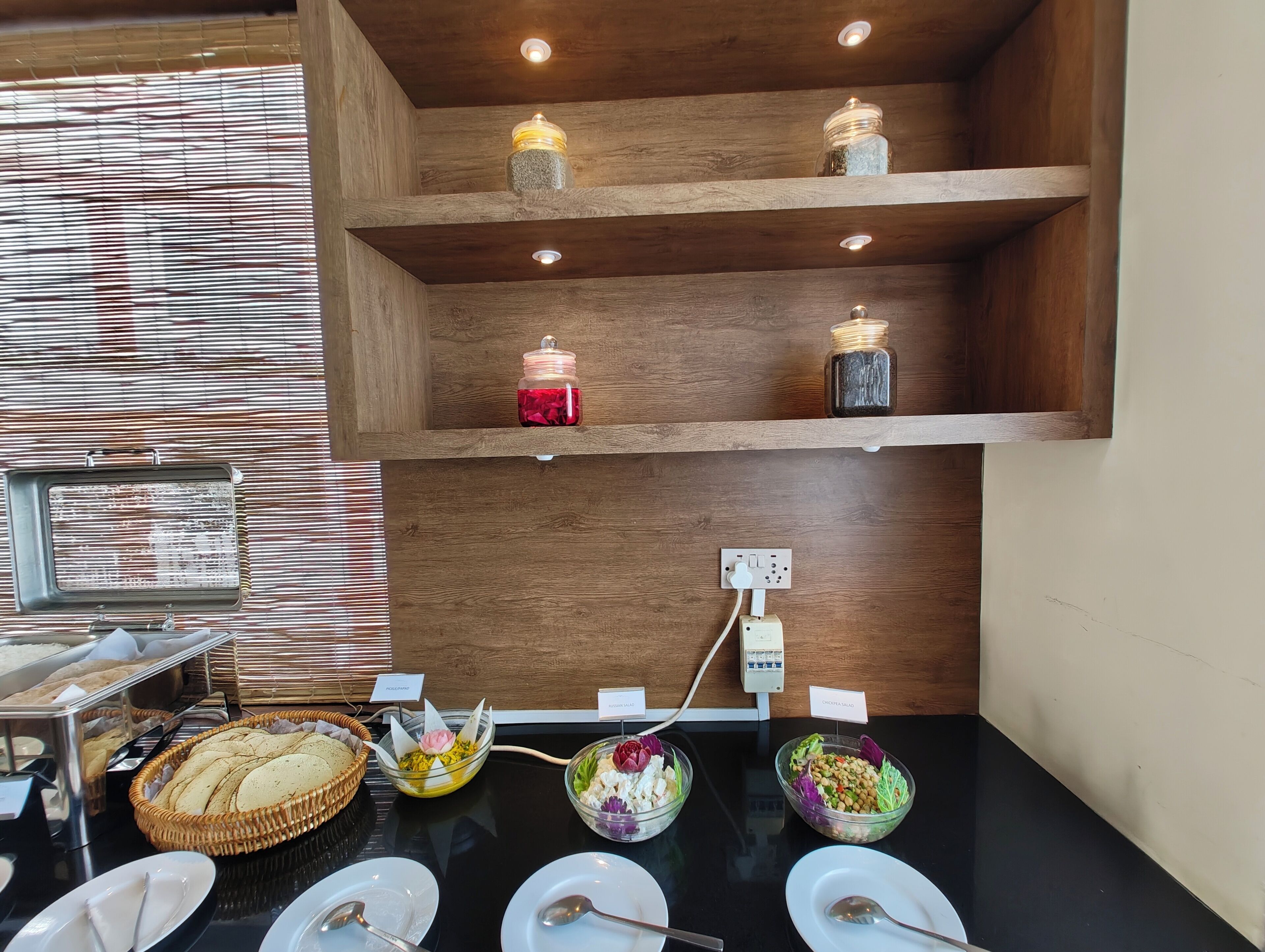 A buffet setup with various food items and a wooden shelf with jars.