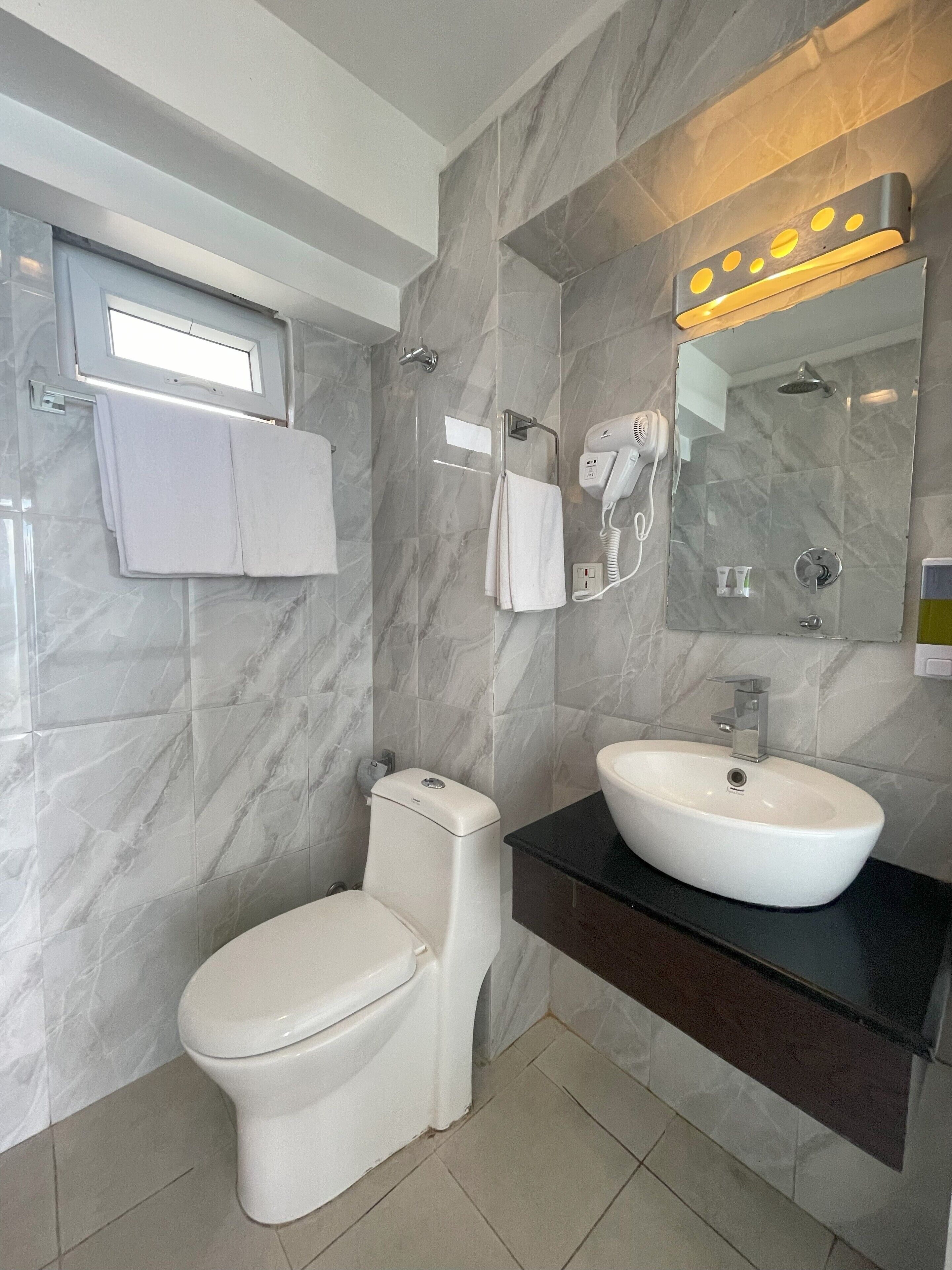 Een moderne badkamer met toilet, wastafel en spiegel.