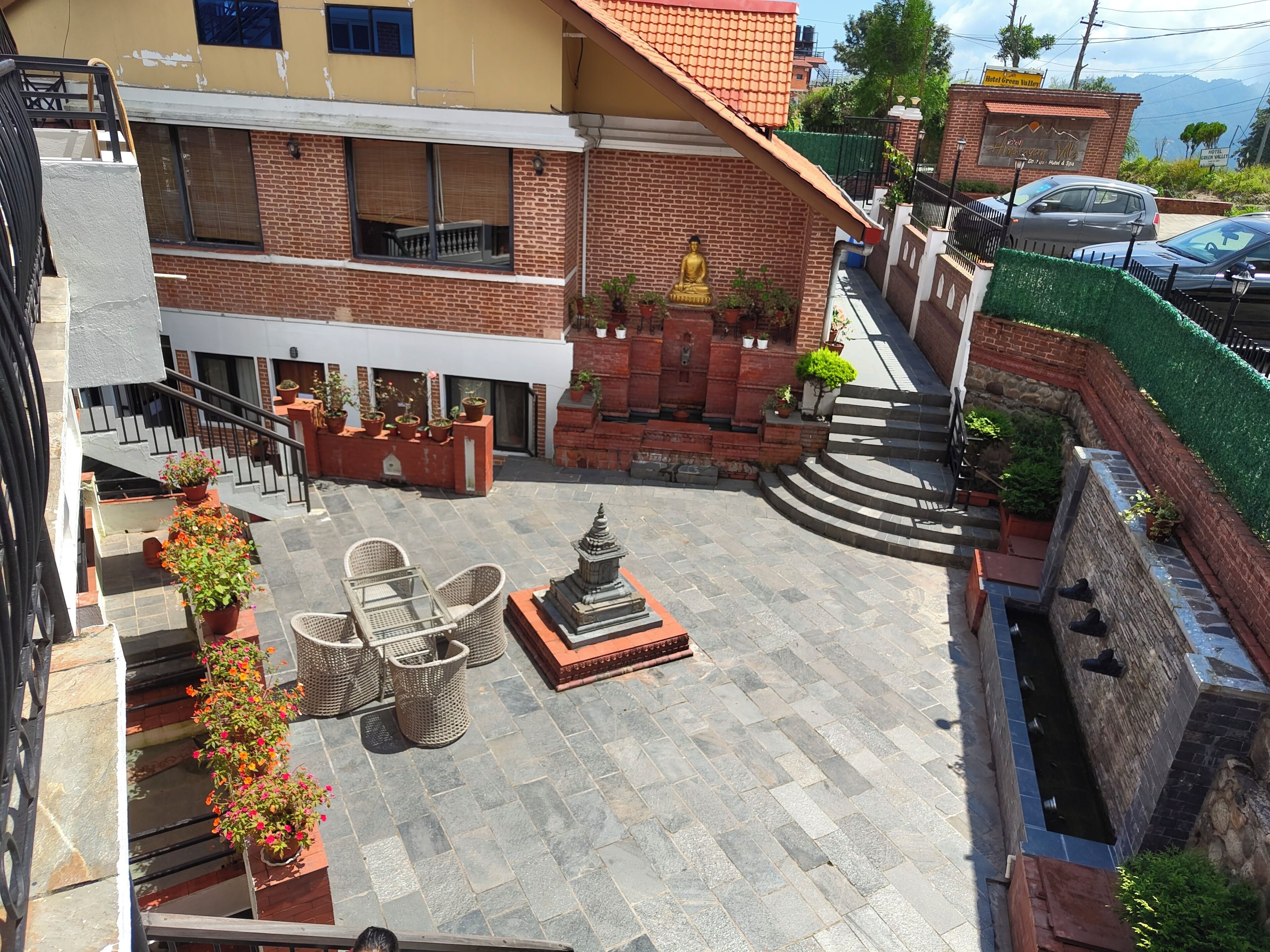 A courtyard with a statue, outdoor seating, and potted plants.