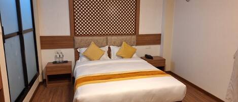 A neatly made bed with a wooden headboard, two bedside tables, and a wall-mounted air conditioner.