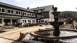 A building with a patio area, a fountain, and a row of windows. - Wittgensteiner Landhaus - Adult Only (Winterberg)