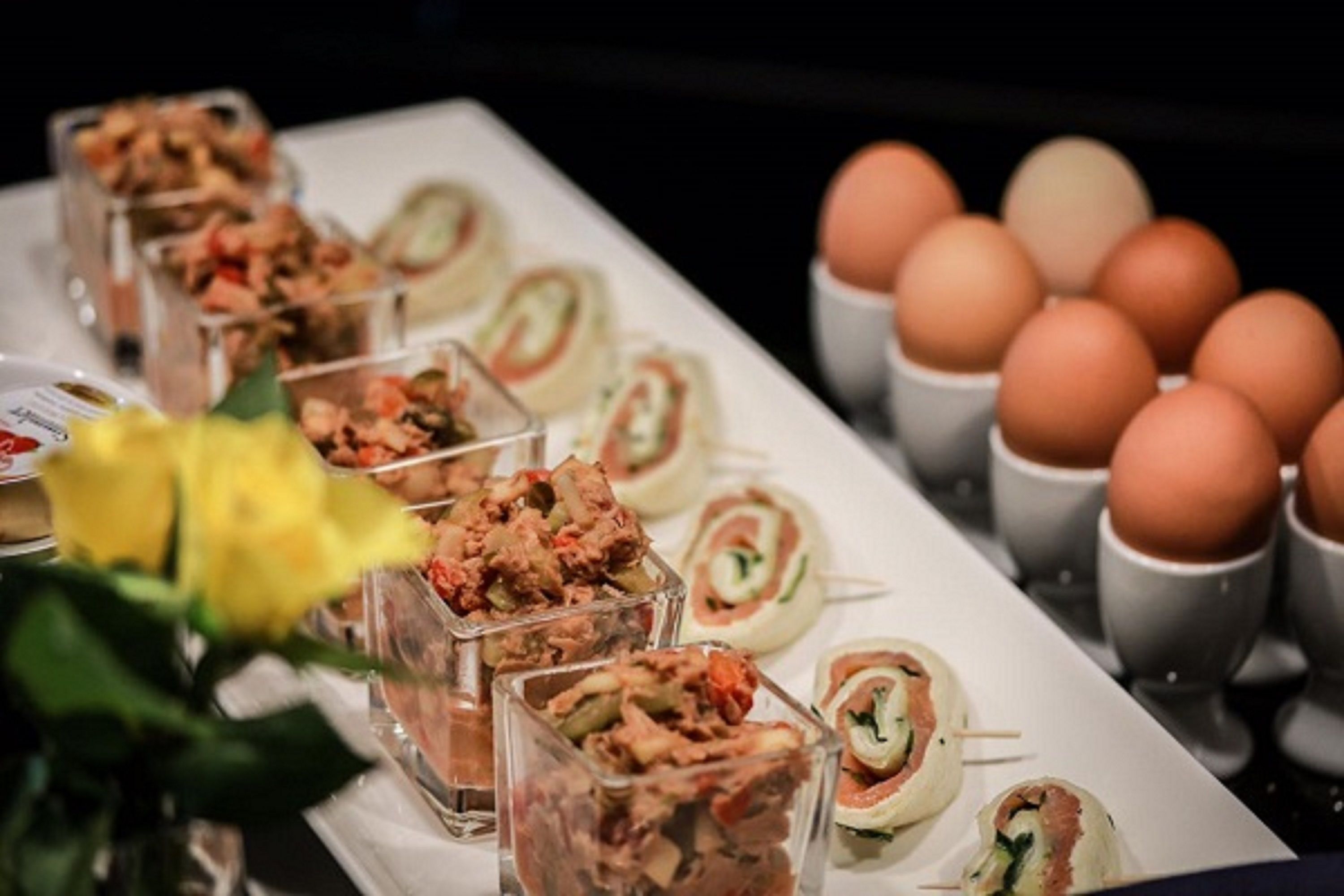 A buffet table with various food items, including rolled sushi and a selection of eggs.