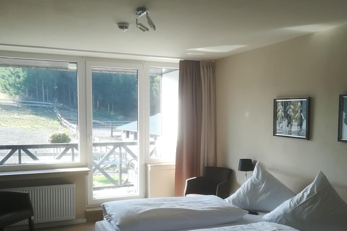 A hotel room with a bed, a desk, a chair, and a window with a view of the outdoors.