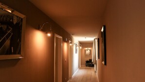 A hallway with a wooden floor, wall-mounted lights, and framed pictures. - Wittgensteiner Landhaus - Adult Only (Winterberg)