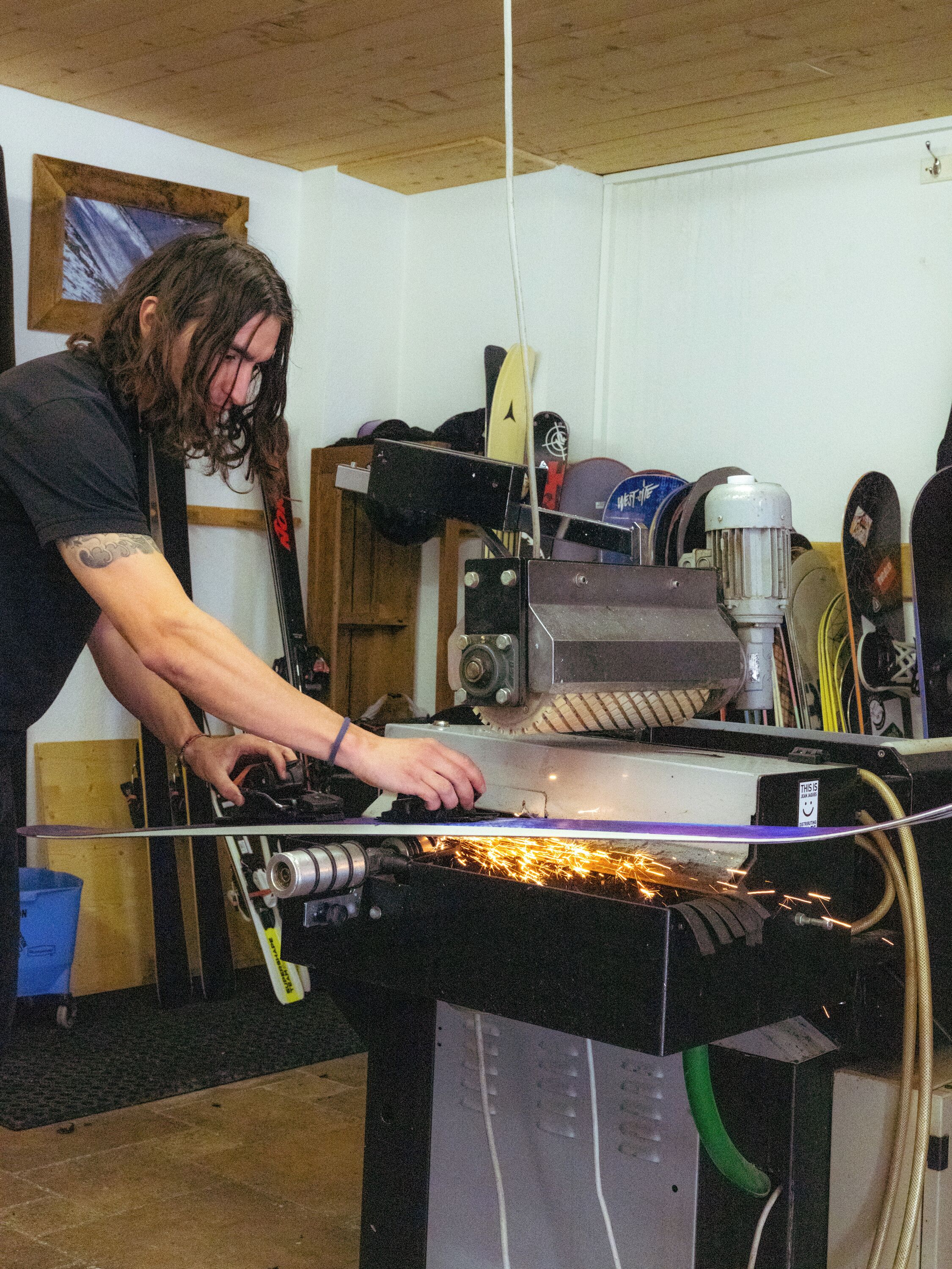 A person operating a machine with sparks, surrounded by various equipment and tools.