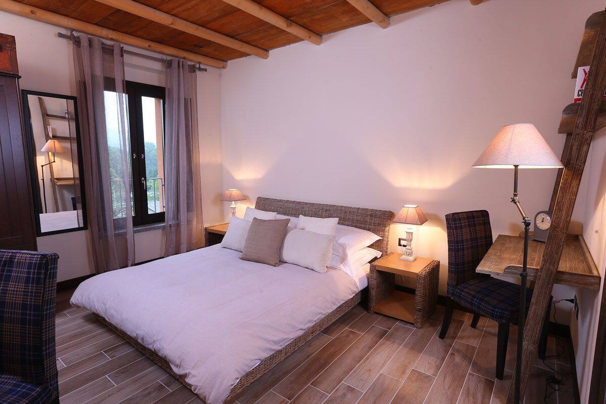 Une chambre à coucher avec un grand lit, deux tables de chevet, une chaise, un bureau et une lampe.