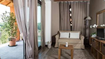Un salon chaleureux avec un canapé beige, une table basse en bois et une grande fenêtre agrémentée de rideaux.