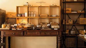 Un escritorio de madera con cajones y estantes que contienen varios utensilios de cocina, como frascos, platos y una tetera.