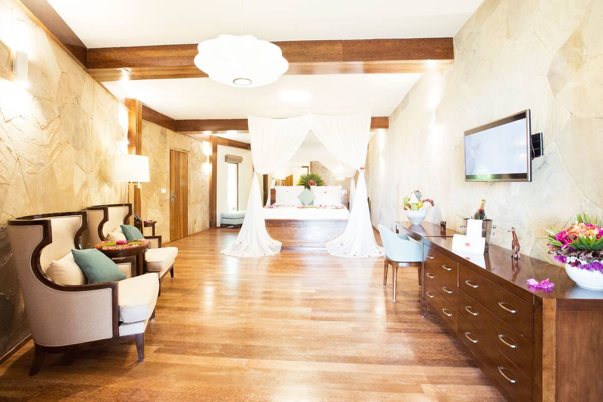 A hotel lobby with a wooden floor, a reception desk, and a seating area with chairs.