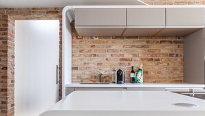 A modern kitchen with a brick wall backsplash, white cabinetry, and a stainless steel sink. - Ringelnatz Inselhotel Malchow (Malchow)