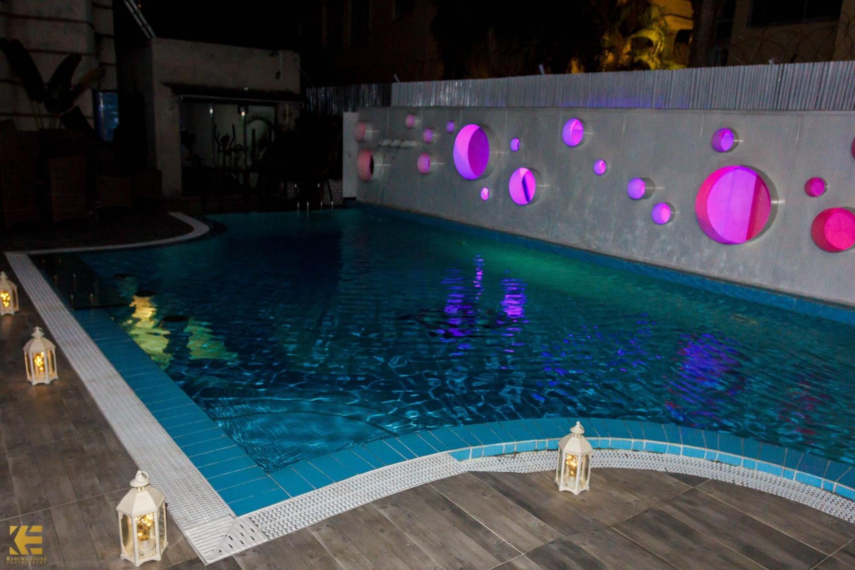 A swimming pool with a tiled edge and a wall with circular cutouts.