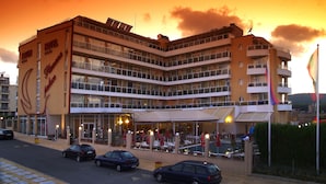 Un hotel de varios pisos con balcones y una zona de restaurante.