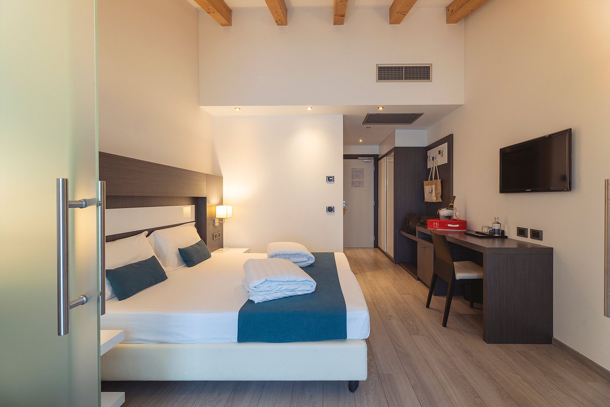 Una camera d'albergo moderna con un letto grande, una scrivania e un televisore.