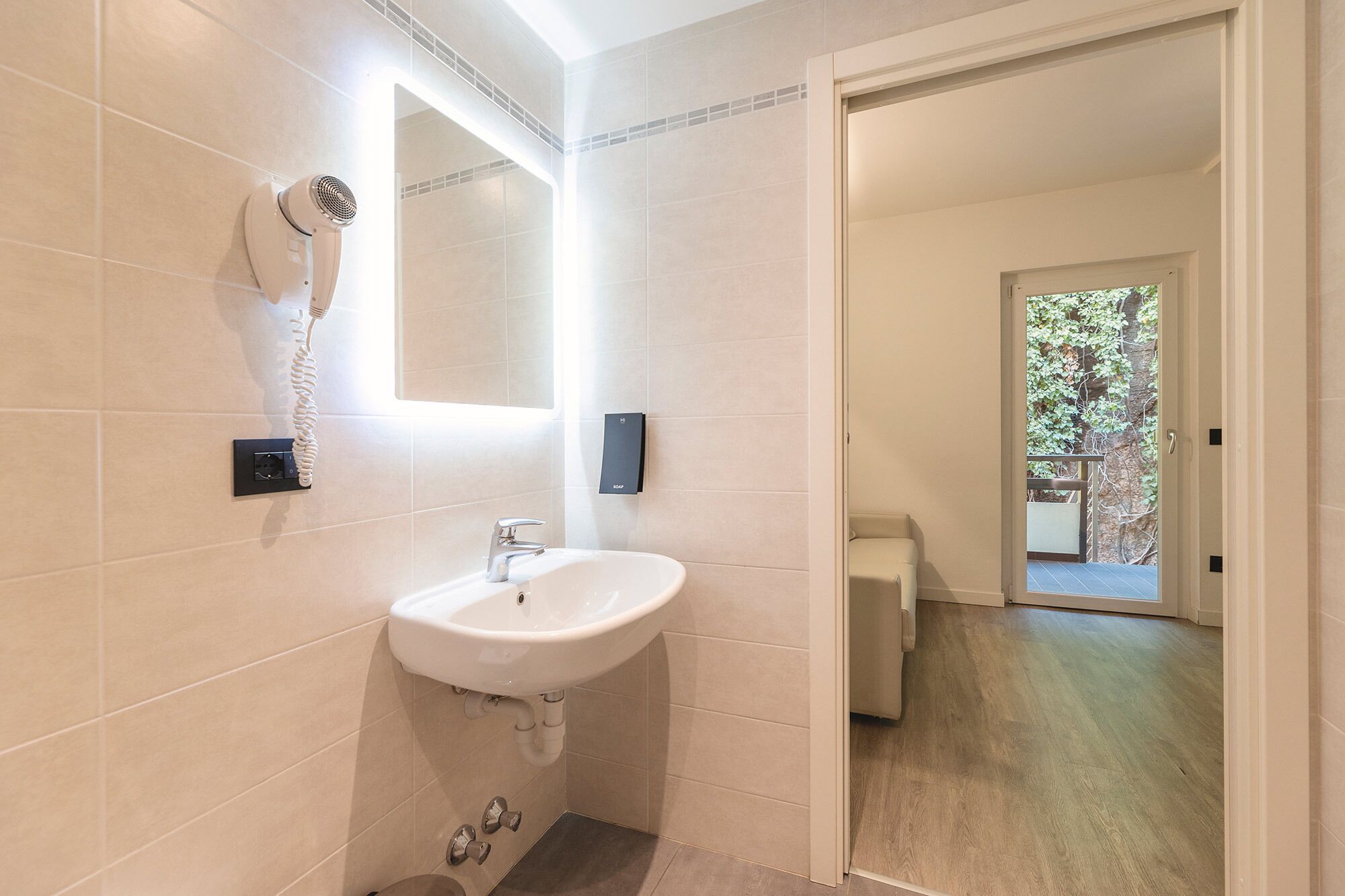 Une salle de bain moderne avec un lavabo blanc, un sèche-cheveux et un miroir.