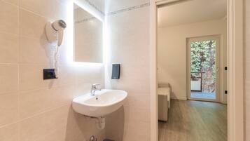 Une salle de bain moderne avec un lavabo blanc, un sèche-cheveux et un miroir.