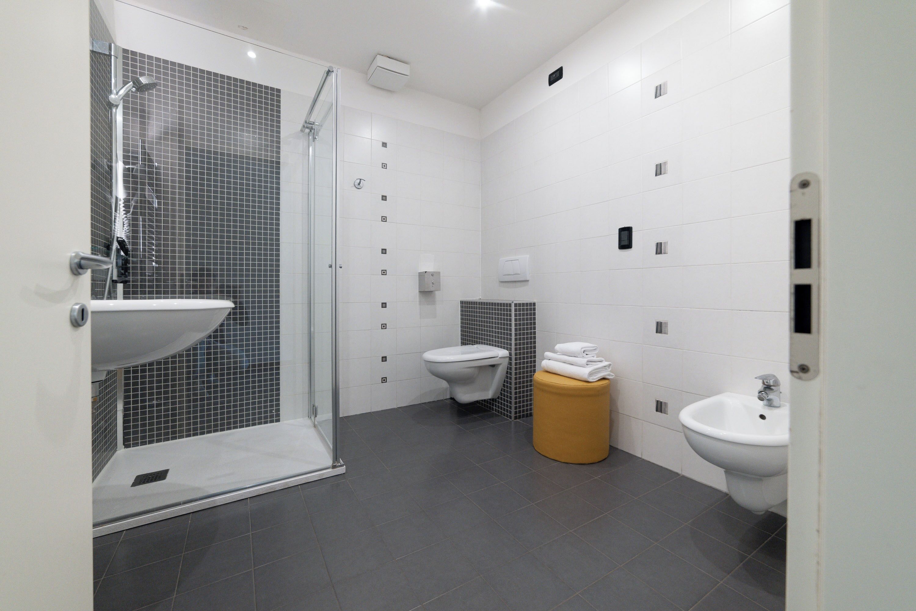 Un bagno moderno con box doccia in vetro, lavandino, wc e bidet.