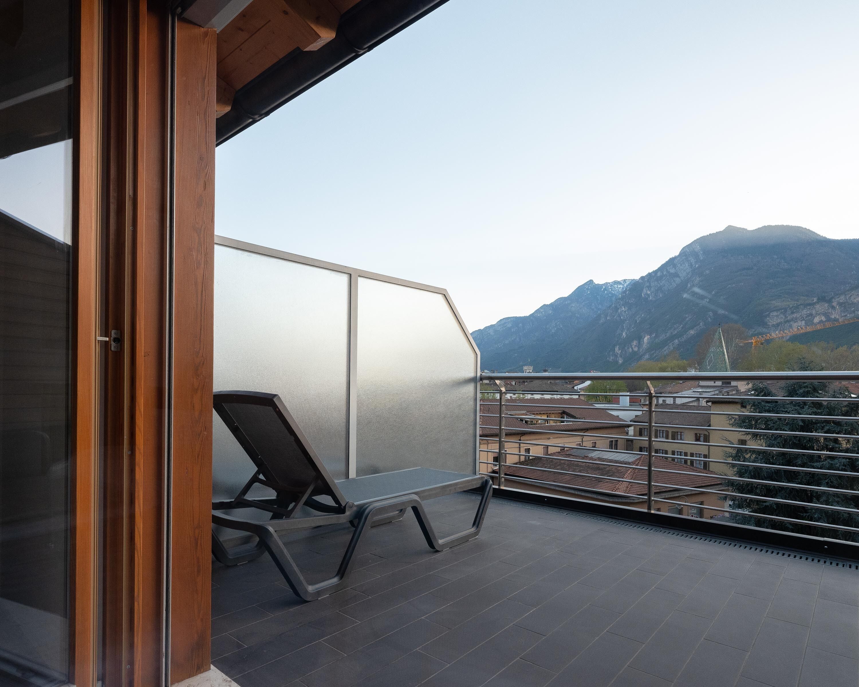 A balcony with a view of mountains, a chair, and a railing.
