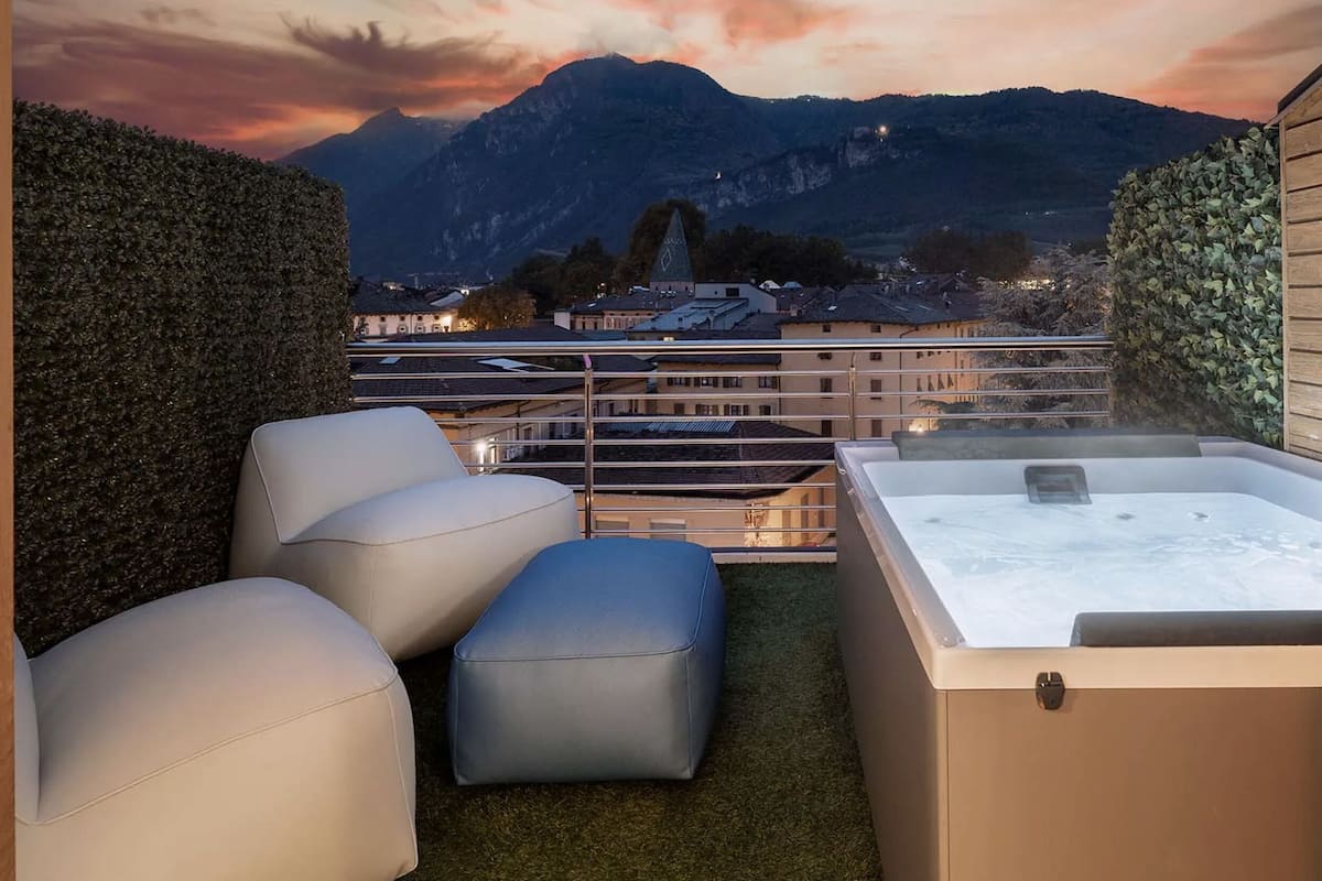 A balcony with a hot tub, seating, and a mountain view.