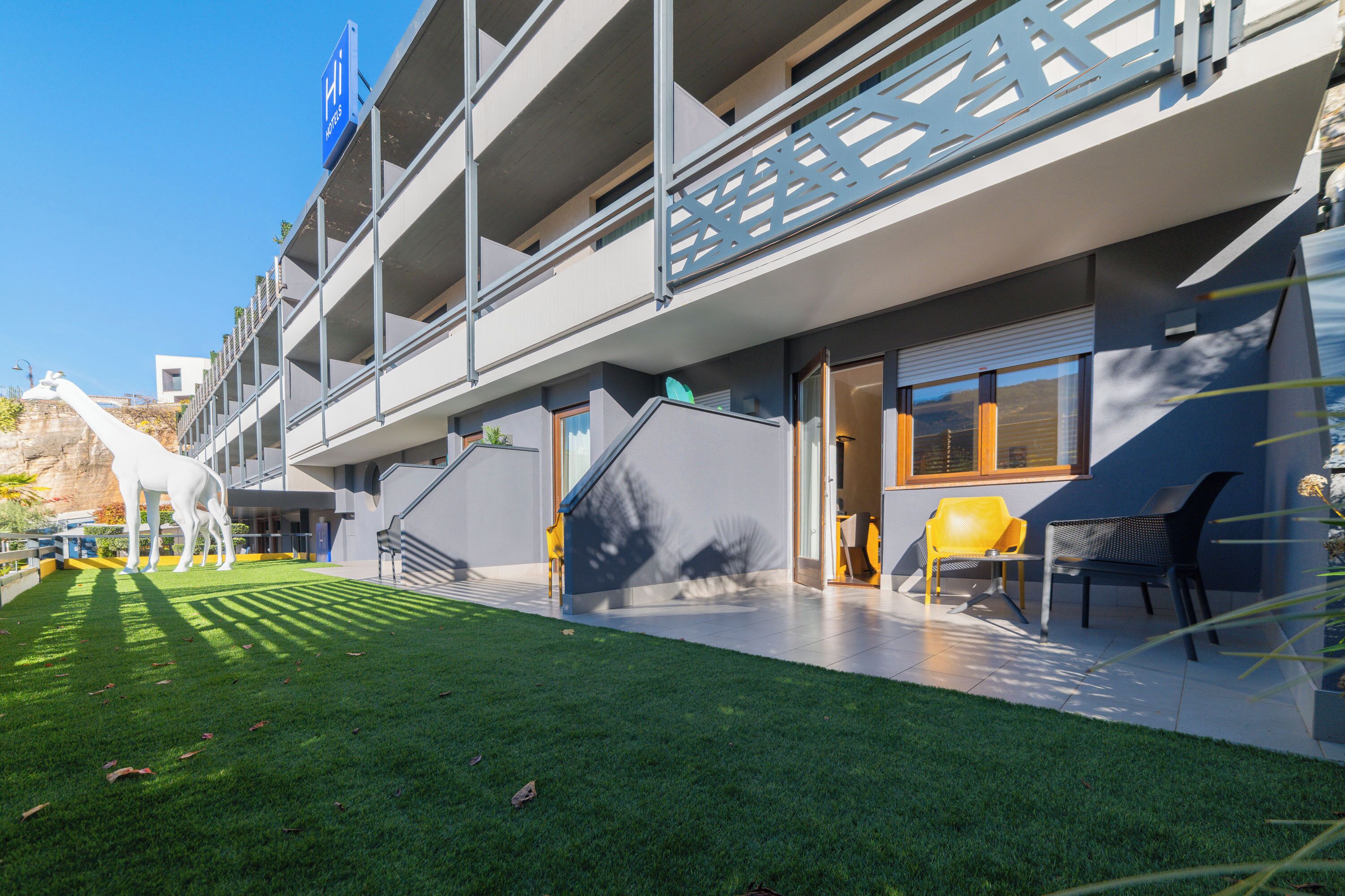 A modern building with a multi-level structure, outdoor seating area, and a well-maintained lawn.