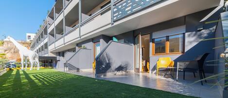 A modern building with a multi-level structure, outdoor seating area, and a well-maintained lawn.
