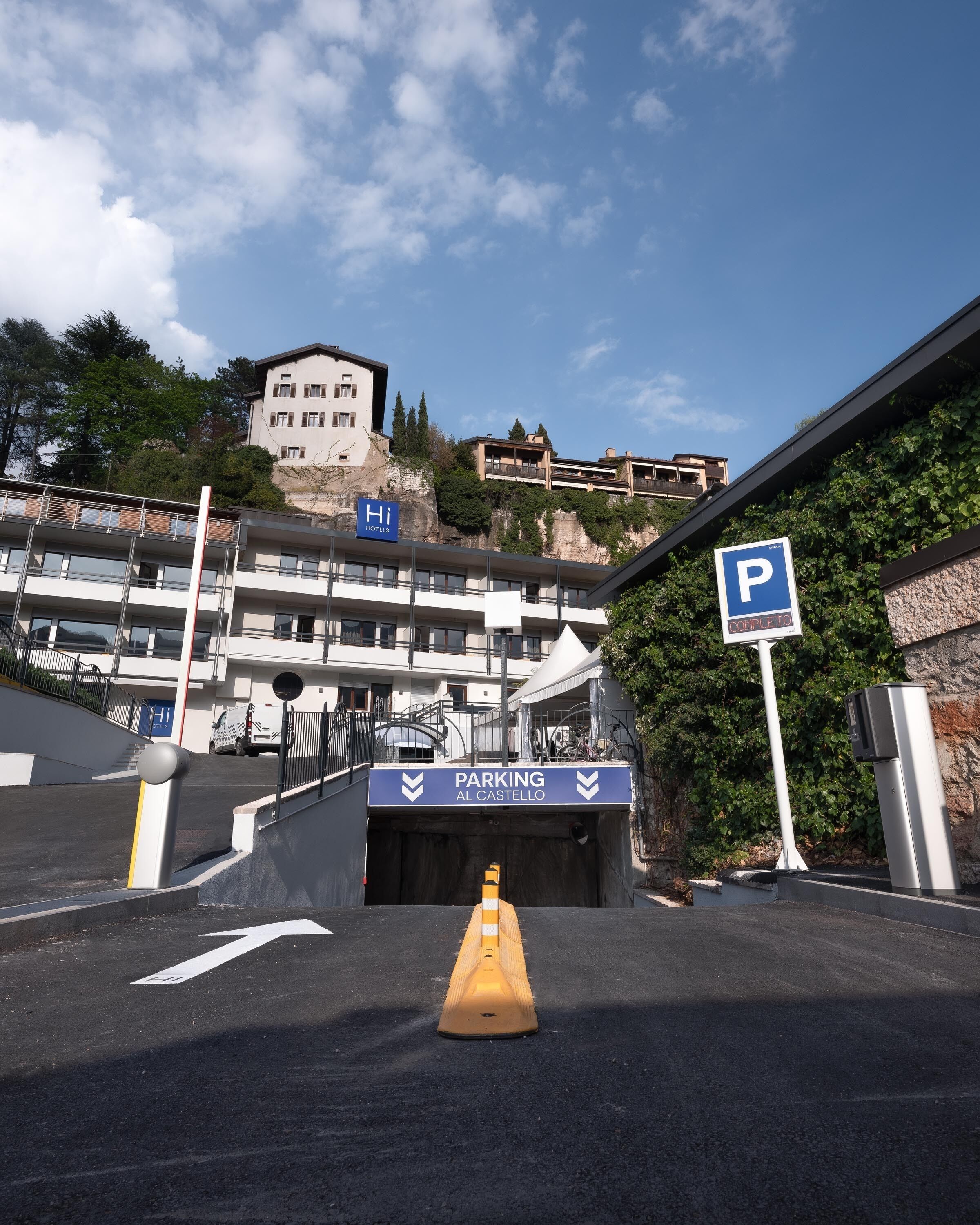 A hotel entrance with a parking sign, a ramp leading to the entrance, and a view of the surrounding buildings.