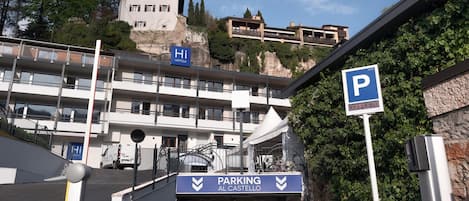 A hotel entrance with a parking sign, a ramp leading to the entrance, and a view of the surrounding buildings.