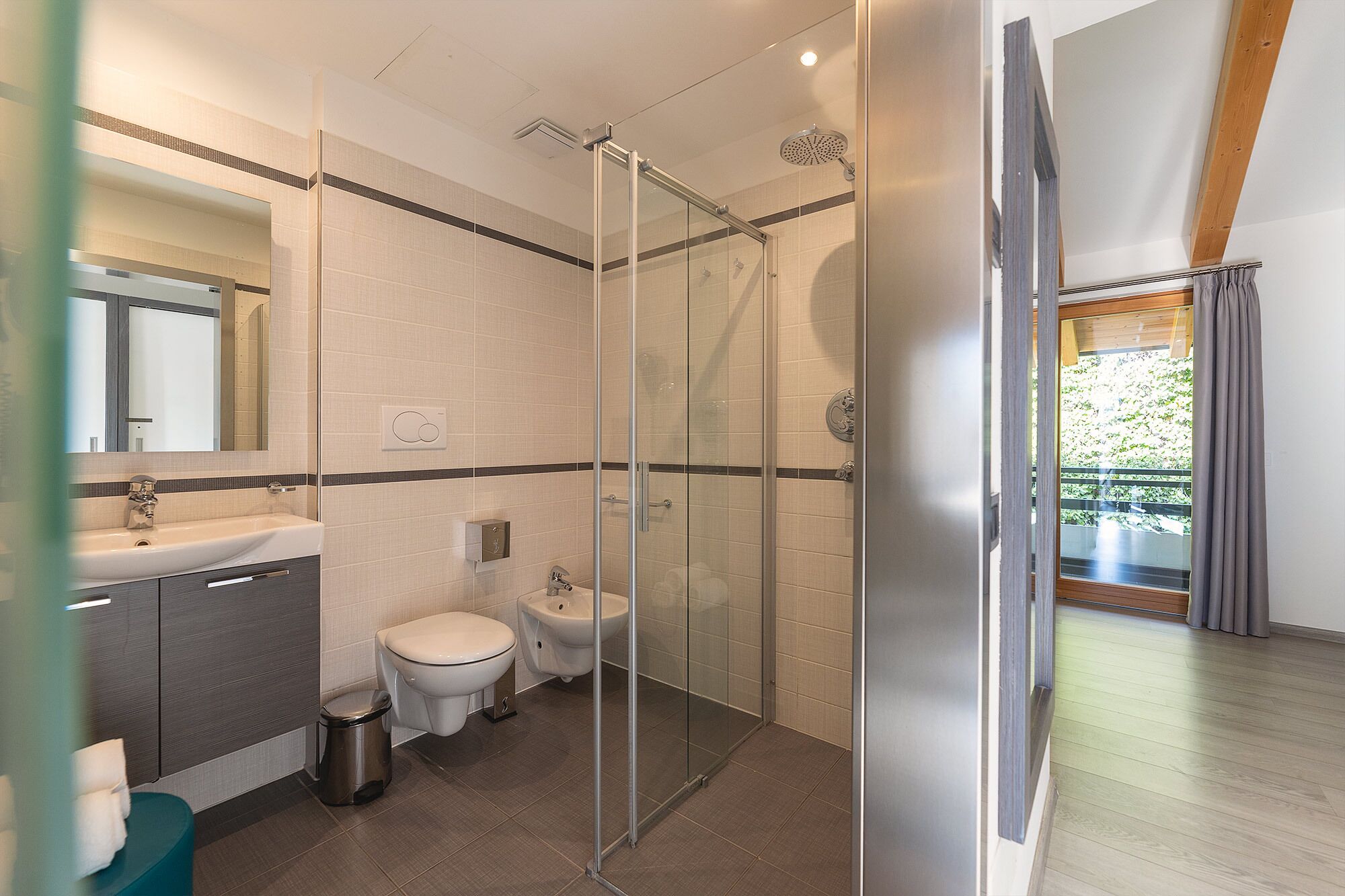 A modern bathroom with a glass-enclosed shower, a sink, and a toilet.