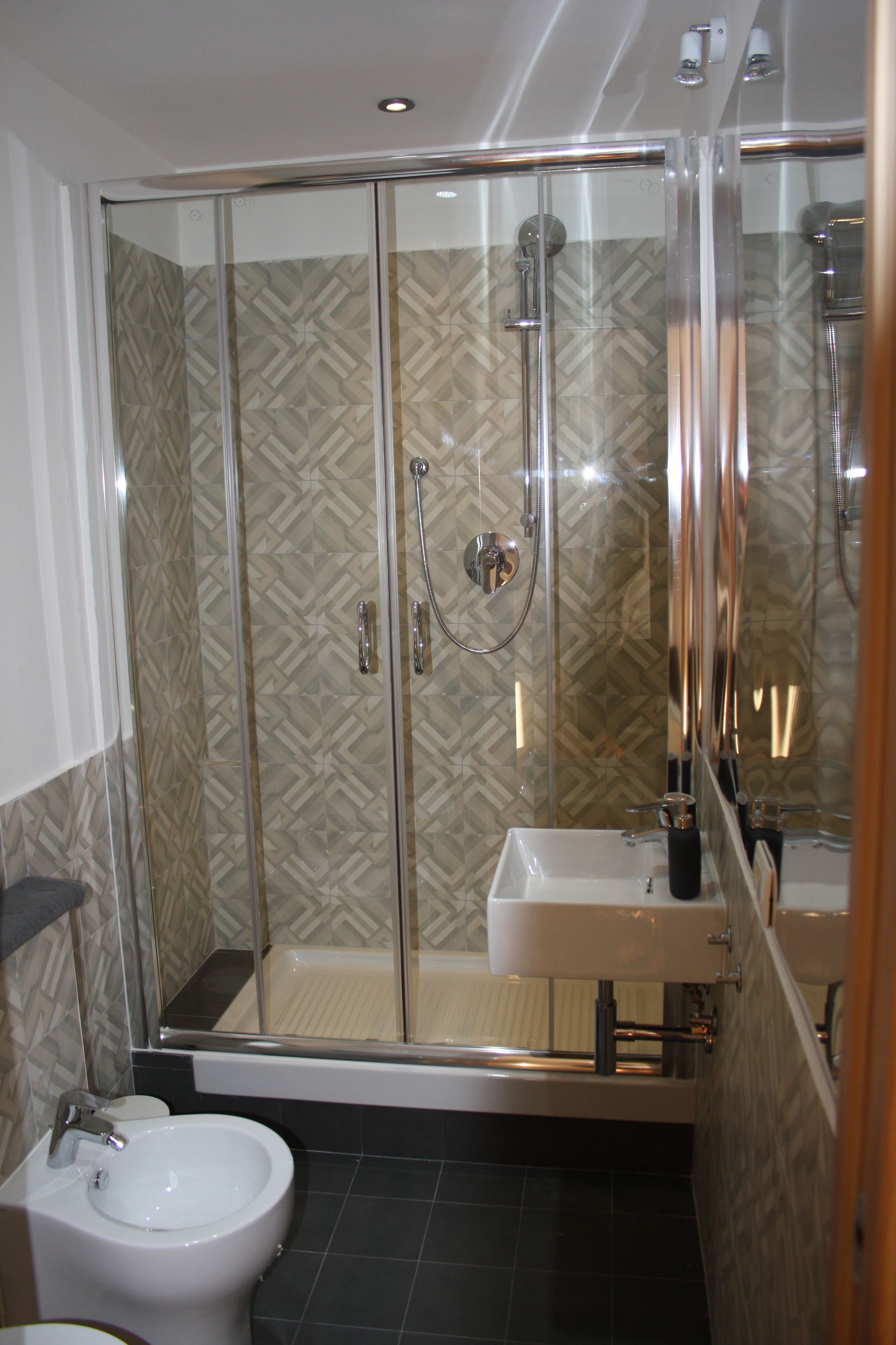 A modern bathroom with a glass-enclosed shower, a white sink, and a bidet.