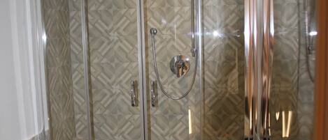 A modern bathroom with a glass-enclosed shower, a white sink, and a bidet.