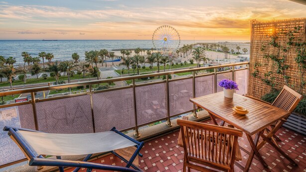 A balcony with a view of the sea and a Ferris wheel, wooden furniture, and a decorative wall. - La Casa sul Mare (Civitavecchia)