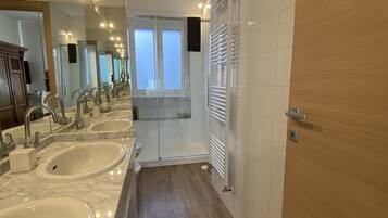 A modern bathroom with three sinks, a large mirror, and a wooden floor.
